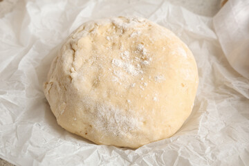 Baking paper with fresh raw dough on white background, closeup