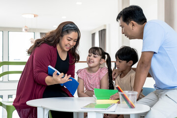 Asian family with father, mother teaching homework to boy and girl , family relationship concept