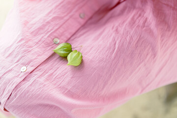 Pink fabric with green leaves resting on it.