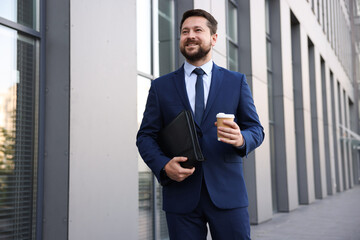 Successful businessman with coffee near office building