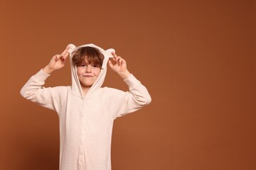 Cute little boy in pajamas on brown background. Space for text © New Africa