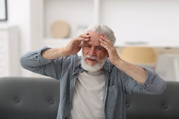 Senior man suffering from headache at home
