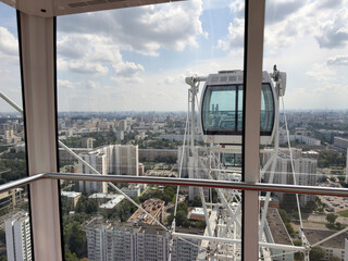 The view from inside a Ferris wheel cabin at a high altitude with the city skyline below. The...