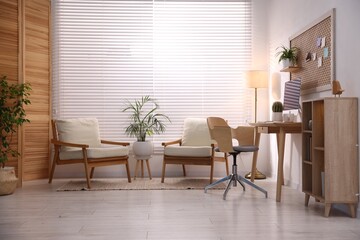 Stylish workplace with wooden desk, computer and armchairs at home office. Interior design