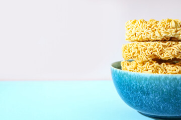 Bowl with raw instant noodles on colorful background