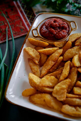 A Delicious Platter of Crispy Golden Potato Wedges Accompanied by a Spicy Tomato Sauce Ideal for Sharing with Friends and Family at Any Gathering