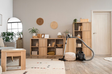 Interior of living room with vacuum cleaner, pouf and bookshelves
