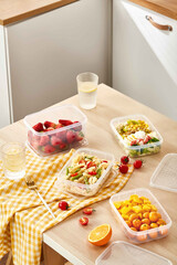 Fresh Food in Clear Plastic Containers on Kitchen Table, Healthy lunch box with mixed fruits and vegetables on table in kitchen