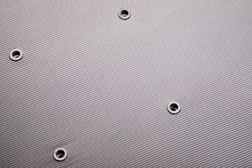 Detailed macro shot of a brushed metal surface featuring diagonal lines and several small screw...