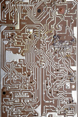Detailed close-up of a vintage brown PCB with silver solder joints, etched copper traces, and signs of heat damage and wear.