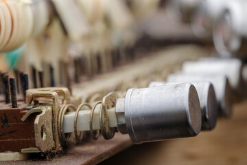 Macro shot of dusty spring-loaded mechanical switches and cylindrical components from an old...
