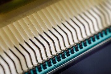 Close-up view of curved metal connector pins soldered to a circuit board, forming a repetitive...