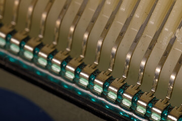 Close-up image showing a row of bent metallic connector pins soldered to a circuit board,...