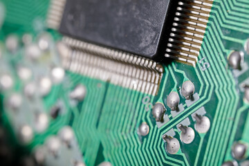 Detailed image showing a black microchip mounted on a green printed circuit board, with fine solder...