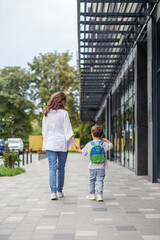 Back to school. Mother and son walking hand in hand to school