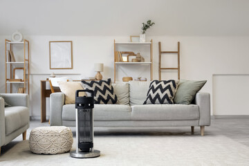 Interior of light living room with sofas, pouf and electric heater