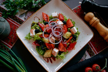 A Fresh Vegetable Salad Featuring Crisp Greens, Juicy Tomatoes, Olives, Feta Cheese, and a Drizzle...