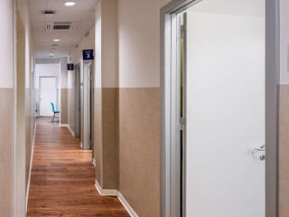 Corridor of a medical clinic with a view of the numbered doors of the doctors offices, wooden...