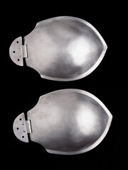 Shiny steel shoulder armor plates with hinge detail, shown front and back on black background.