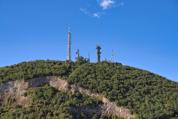 Telecommunication antennas towering over green hill in calaone, italy