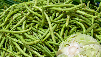 Fresh green beans and a halved cabbage displayed together, showcasing vibrant colors and textures of farm-fresh produce.