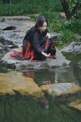 Young woman in traditional attire by tranquil water.