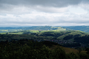 Fototapeta premium Scenic Countryside Landscape with Rolling Hills and Overcast Sky