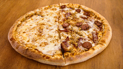 A sliced pizza with two different toppings, cheese and sausage, on a wooden surface.