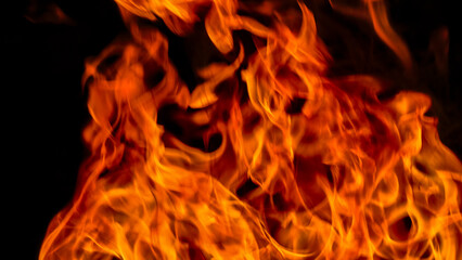 Fototapeta premium Intense flames burning brightly against a dark, black background, showing heat and energy.