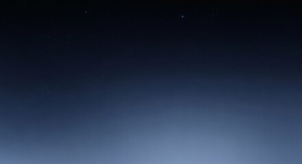 A serene view of the deep night sky with a few faint stars, showing a dark blue gradient to a light haze on the horizon.