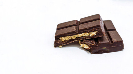 Broken pieces of dark chocolate bar with creamy filling, revealing its delicious interior.