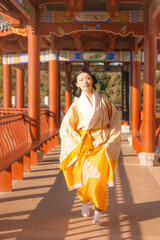 Young Asian woman in traditional clothing walking in a garden.