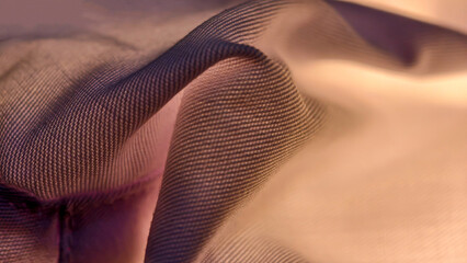 Close-up of a translucent, draped fabric with a visible mesh texture, displaying a gradient of...