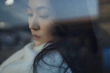 Pensive young Asian woman with long hair.
