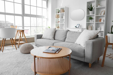 Interior of light living room with grey sofa, workplace and mirror