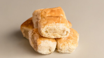 Stack four freshly baked banana bolen, golden brown, on a neutral surface, showing off their soft texture