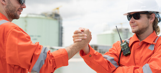 Two male worker join hands together at natural gas separation plant offshore. Unity and teamwork concept