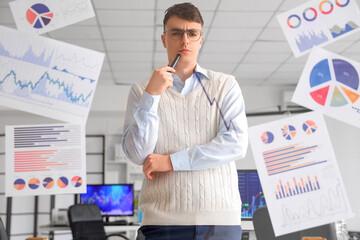 Thoughtful male trader looking at drawn up arrow and diagrams on glass in office