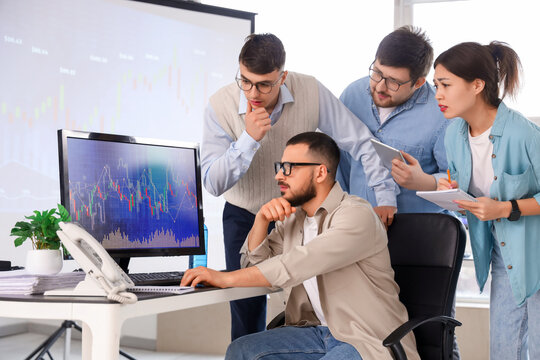 Team of traders working at table in office