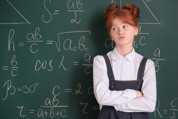 Thoughtful schoolgirl near chalkboard. Children's Inventor's Day