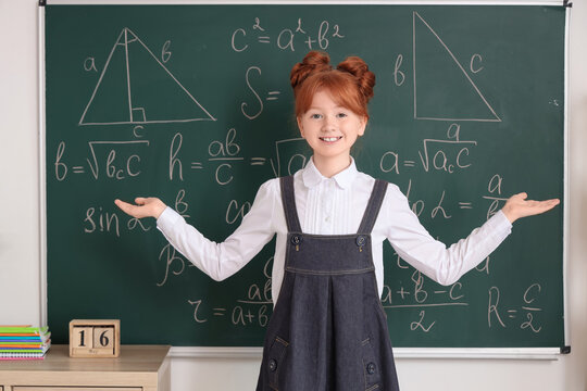 Cute schoolgirl near chalkboard in classroom. Children's Inventor's Day