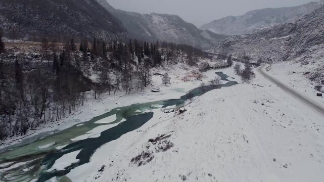 a mountain river and a road running nearby in winter. View from above
