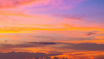 A vibrant sky transitions from deep blue at the top to a warm orange hue near the horizon, creating a stunning sunset backdrop filled with soft clouds.