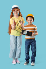 Cute inventors in hardhats with battery tester on blue background