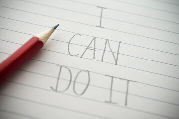 Close up I can do it handwriting on paper notepad background with pencil. Creative motivation, inspiring quotes, leadership in business, education and so on concept.