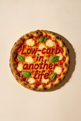 Funny Pizza with Mozzarella and Basil, Typography Quote “Low-Carb in Another Life” Written in Sauce – Ironic Food Concept, Flat Lay on Neutral Background, Burnt Crust Neapolitan Style