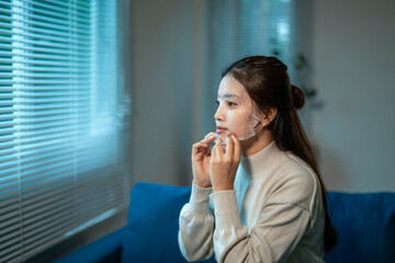 Young woman applying cosmetic face mask at home