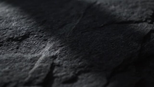 Dark gray surface with textures showing variations in lighting and shadow