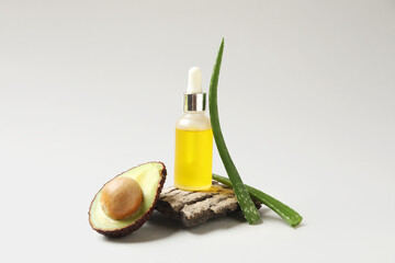 Composition with bottle of cosmetic product, tree bark, avocado and aloe vera leaves on white...