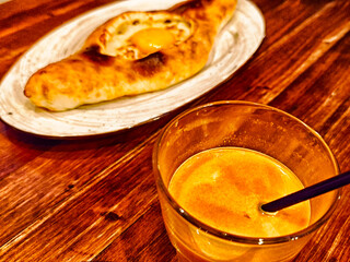 Traditional pastry with egg and orange drink on wooden table in cozy setting during evening